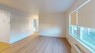 This 520 square foot apartment in Brockton, MA offers a well-designed living space with one bedroom and one bathroom. The interior showcases a modern aesthetic with clean lines and a neutral color palette. Light wood flooring runs throughout, creating a sense of warmth and continuity.

The living area is spacious and bright, featuring large windows that allow natural light to flood the room. Roller blinds provide privacy when needed. The bedroom, measuring 160 square feet, includes ample closet space with white paneled doors.

The bathroom is fitted with a white vanity, a large mirror, and a shower/tub combination. A window in the bathroom offers natural light and ventilation. The kitchen, while compact, is efficiently designed with white cabinetry, a gas stove, and a microwave.

The apartment's layout maximizes the use of space, with two distinct living areas in addition to the bedroom and kitchen. These could serve as a dining area and a living room or be adapted to the occupant's needs.

Throughout the apartment, baseboard heating units ensure comfort in colder months. The crisp white walls and ceiling create a blank canvas for personalization, while also contributing to the overall sense of spaciousness in this cozy urban dwelling.