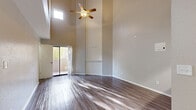 This two-story home in Sunland Park, New Mexico, offers a well-designed layout across two floors, with three bedrooms, two bathrooms, and thoughtful architectural details throughout. The main floor immediately impresses with dramatic vaulted ceilings in the living room, bathed in natural light from a high clerestory window and sliding glass door that opens to the outdoors. Rich wood-look flooring flows through the main living areas, while a distinctive arched entryway frames the staircase, adding a touch of elegance to the open floor plan. The kitchen features grey cabinetry, light marble-style countertops, and black stainless appliances including a refrigerator, electric range, and built-in microwave, all set on durable wood-look flooring. Both bathrooms are finished with clean white tile surrounds and tub-shower combinations. Upstairs, the bedrooms are carpeted for comfort and each includes a ceiling fan, with select rooms offering private sliding glass door access to outdoor views. Three closets provide ample storage throughout. The two full bathrooms are efficiently appointed. The home's neutral color palette, vaulted living space, and functional floor plan make it a versatile and inviting residence in the Sunland Park area.