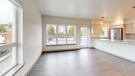 Located at 110 Roy St in Seattle's Queen Anne neighborhood, this modern 2-bedroom, 2-bathroom residence offers a thoughtfully designed single-floor layout. Hardwood-style flooring flows consistently throughout, complementing the clean, neutral palette of crisp white walls and contemporary finishes.

The open-concept kitchen serves as a centerpiece of the home, featuring a large waterfall-edge island with an undermount sink, light wood cabinetry, quartz countertops, stainless steel appliances, and stylish pendant lighting. The spacious living area is bathed in natural light from an expansive floor-to-ceiling window wall, offering views of the surrounding Seattle cityscape.

Both bedrooms are well-proportioned with large windows that frame neighborhood views, providing ample natural light. Each room includes wall-mounted mini-split HVAC units for individual climate control. A dedicated closet adds practical storage to the layout.

The two bathrooms are finished with light wood vanity cabinetry, quartz countertops, large mirrors, and wood-look tile flooring. One bathroom features a glass-enclosed walk-in shower, while the second includes a full soaking tub. A connected hallway ties all spaces together efficiently, creating a cohesive and functional flow throughout the home.