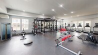 Located at 1000 Archive Cir in Oxford, Mississippi, this fitness center offers a generously sized, single-floor exercise facility designed to accommodate a wide variety of workout needs. The space is thoughtfully laid out to maximize functionality and flow, featuring durable dark rubberized flooring throughout that is well-suited for high-intensity training.

The strength training area is extensively equipped, showcasing a multi-station power rack system with barbells and weight plates, a full dumbbell rack, adjustable benches, and a selection of cable and resistance machines. A large wall-mounted mirror runs along one section of the floor, enhancing the sense of space and allowing users to monitor their form during exercise.

The dedicated cardio zone includes multiple Matrix-brand treadmills and stair climbers, each equipped with individual display screens for tracking workout metrics. Additional cable and weight machines are distributed throughout the space to support targeted muscle training.

Natural light filters in through multiple windows fitted with blinds, complemented by recessed ceiling lighting that ensures the space remains bright and welcoming throughout the day. The clean white walls and open layout contribute to an airy, modern atmosphere. Safety features, including a mounted fire extinguisher, are also present. The overall design reflects a well-appointed, community-level fitness facility built for serious and recreational athletes alike.