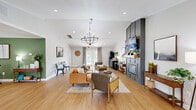 Located at 788 Sea Horse Cir in Rural Hall, NC, this single-story space is thoughtfully designed to balance comfort and functionality. Light hardwood flooring flows throughout, unifying the layout and contributing to a warm, welcoming ambiance.

The living room serves as the centerpiece of the space, anchored by a striking gray built-in fireplace surround topped with a wall-mounted television and a rustic wood shelf. Vaulted ceilings with a beadboard finish add architectural interest and a sense of openness, while a statement chandelier with candle-style lighting provides a refined focal point. Recessed lighting supplements natural light that streams in through multiple windows and glass-paneled exterior doors, offering views of the surrounding greenery. The seating area is arranged around a central rug, creating an inviting gathering space. A small bistro-style dining nook near the entrance adds versatility.

The office area, styled as a cyber café, features a long granite-topped counter with bar-height seating, computer workstations, and a bold sage-green accent wall adorned with decorative wooden artwork. This focused workspace is compact yet efficiently outfitted. An adjacent nook with its own green accent wall provides additional workspace and display area, completing this well-rounded, multi-purpose environment.