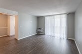 Located at 10280 La Hacienda Ave in Fountain Valley, California, this single-floor residence offers a well-designed layout with consistent wood-style flooring throughout. The open living area is bright and airy, featuring neutral gray walls, a textured ceiling, and a sliding glass door fitted with vertical blinds that allows natural light to flow in while providing access to an outdoor area. A wall-mounted AC unit serves the living space for year-round comfort.

The kitchen is efficiently laid out in a galley style, featuring white cabinetry, granite-style countertops, a stainless steel sink, and black appliances, including an electric range. A window above the counter fills the space with natural light and garden views.

The bedrooms are generously sized, each equipped with ceiling fans and sliding glass doors or windows dressed with vertical blinds or horizontal blinds, inviting ample daylight. One bedroom features mirrored sliding closet doors, enhancing the sense of space.

The bathroom is well-appointed with a dual-sink vanity topped with granite-style counters, a wide mirror with vanity lighting, built-in cabinetry for storage, and wood-style flooring. Louvered doors and additional built-in linen storage add practical functionality throughout the home.