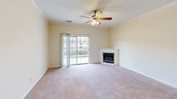 Located at 200 Atrium Way in Columbia, SC, this well-appointed two-bedroom, two-bathroom single-floor residence offers a comfortable and functional layout. The living room serves as the heart of the home, featuring a corner fireplace with a classic white mantle, plush carpeting, crown molding, a ceiling fan with light fixture, and a sliding glass door that fills the space with natural light and provides access to an outdoor area. The kitchen is outfitted with gray cabinetry, granite countertops, stainless steel appliances including a refrigerator and dishwasher, and light hardwood-style flooring that flows into an adjacent dining or flex space. A pass-through connects the kitchen to the hallway leading to the bedrooms. The spacious primary bedroom features soft carpeting, a ceiling fan, and access to a closet and a full bathroom with a soaking tub and tiled surround. The second bedroom is equally well-sized with carpeting and an adjoining closet. Both bathrooms include full tub-and-shower combinations. A dedicated laundry room with hardwood-style flooring and built-in shelving adds everyday convenience. The neutral color palette and consistent finishes throughout create a clean, cohesive ambiance.