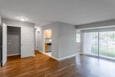 This single-floor residence offers a well-organized layout that balances common living spaces with private quarters. The living area is a standout feature, showcasing warm hardwood flooring and neutral beige walls that create a bright, welcoming atmosphere. A large sliding glass door fitted with vertical blinds floods the space with natural light while providing views of the surrounding greenery outside.

The galley-style kitchen is efficiently designed, lined with honey-toned wood cabinetry extending to the ceiling for ample storage. Granite countertops provide durable workspace, complemented by stainless steel appliances including a range with microwave above and a refrigerator. A stainless steel sink and dishwasher complete the functional setup, with light tile flooring underfoot.

The bedroom is generously proportioned, featuring plush neutral carpeting and access to a dedicated walk-in closet with built-in shelving. The bathroom includes a full tub-shower combination with white tile surround, a granite-topped vanity with wood cabinetry, and tile flooring. A secondary bathroom with a tub-shower unit and tile flooring provides additional convenience. White panel doors and clean white trim throughout contribute to a cohesive, polished interior aesthetic.