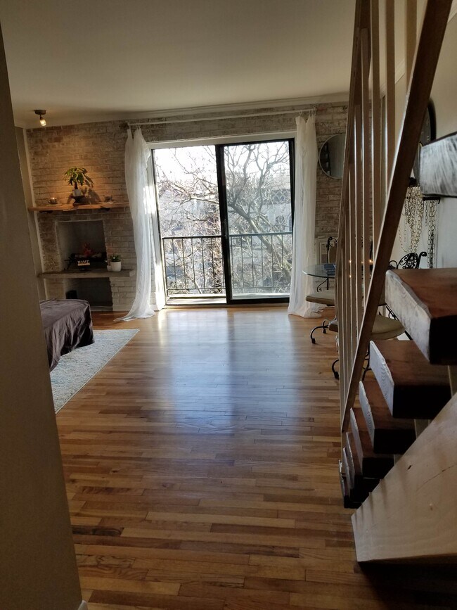 Main Floor Living Room | Wood-burning Fireplace | South Facing Balcony | Exposed Brick Wall - 832 W Oakdale Ave