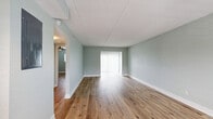 Located at 6750 Gulfport Blvd S in South Pasadena, FL, this thoughtfully updated one-bedroom, one-bathroom unit offers a cohesive and modern interior throughout its single-floor layout. Light hardwood flooring flows seamlessly across every room, complemented by soft sage-green walls and crisp white trim that create a calm, coastal aesthetic.

The open living room is bright and airy, featuring a ceiling fan and large sliding glass doors dressed with vertical blinds that frame a picturesque waterfront view, flooding the space with natural light. A closet off the living area adds convenient storage. The layout connects naturally to a separate dedicated living room area, offering flexible use of space.

The kitchen is well-appointed with grey shaker-style cabinetry, light quartz countertops, a subway tile backsplash with a decorative mosaic accent, and a full suite of stainless steel appliances including a refrigerator, range, microwave, and dishwasher. Track lighting above adds a contemporary touch.

The bedroom is generously sized, equipped with a ceiling fan, a window with natural light, and access to both a hallway and a dedicated walk-in closet with built-in shelving. The bathroom features a tub-shower combination with white tile surround, a mosaic accent border, a vanity with storage, and matching hardwood-style flooring. Two hallways connect the rooms efficiently, completing this well-organized and attractively finished home.
