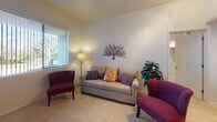 This single-floor model unit at 12730 Monte Vista in Poway offers a well-designed layout that balances comfort and functionality. The open-concept living and dining area is bright and inviting, featuring plush carpeting, vaulted ceilings, and large windows dressed with vertical blinds that allow generous natural light and views of the surrounding greenery. A pass-through window connects the dining area to the kitchen, which is equipped with stainless steel appliances, warm wood cabinetry, and recessed lighting. The dining space comfortably accommodates a full dining set, making it ideal for everyday meals or entertaining. A versatile den or flex room features built-in shelving, track lighting, and a wide sliding door, offering additional functional space. The bedroom is carpeted and bright, with a large window framing outdoor views. Both bathrooms are finished with granite countertops, warm wood vanities, and tile flooring. One bathroom is notably accessibility-friendly, featuring a roll-under vanity, grab bars, and a spacious roll-in shower with a built-in seat. Throughout the unit, clean white walls, soft neutral tones, and consistent finishes create a cohesive and welcoming atmosphere well-suited to comfortable living in Poway.