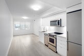 Located at 44 Lillian St, Unit 208 in Toronto, this three-bedroom unit offers a well-designed single-floor layout with a clean, modern aesthetic. The interior is finished with light hardwood flooring throughout, crisp white walls, and white trim, creating a bright and cohesive atmosphere across all rooms.

The kitchen is a standout feature, outfitted with sleek, flat-front white cabinetry extending to the ceiling for ample storage. Stainless steel appliances — including a range, over-the-range microwave, dishwasher, and full-size refrigerator — complement the white tile backsplash and light countertops, delivering a contemporary and functional cooking space.

The primary bedroom is a comfortable size and benefits from two windows that bring in natural light and offer views of the surrounding Toronto neighbourhood. The additional bedrooms are well-proportioned, with one featuring a mirrored sliding closet door and another equipped with a built-in HVAC unit integrated flush into the wall. A hallway connects the bedrooms, maintaining an efficient and practical flow throughout the unit.

Overall, the unit presents a minimalist, move-in-ready interior well-suited for urban living in Toronto.