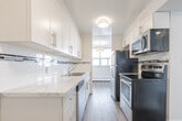 Located at 2 Quebec Street in Guelph, Ontario, this one-bedroom, one-bathroom unit offers a thoughtfully designed layout across a single floor. Light-toned laminate flooring runs throughout, creating a clean and cohesive aesthetic in every room.

The living room is a standout space, featuring a full wall of large windows and a glass-paneled door that fills the room with natural light and offers sweeping outdoor views of the surrounding Guelph landscape. Baseboard heating runs along the perimeter, ensuring year-round comfort.

The kitchen is well-equipped and stylishly finished, featuring white shaker-style cabinetry, marble-look quartz countertops, a classic white subway tile backsplash, and stainless steel appliances including a dishwasher, electric range, and microwave. The galley layout maximizes functionality within the space.

The dining area, adjacent to the kitchen, is defined by a pendant light fixture and benefits from a nearby window, keeping the space bright and inviting.

The bedroom is a comfortable, quiet retreat with a large double-door closet offering ample storage, neutral grey walls, and continued laminate flooring. A window provides natural light and outdoor views.

The bathroom includes a full soaker tub with shower, a vanity with stone-look countertop, and large-format tile surrounds, offering a clean and practical finish throughout.