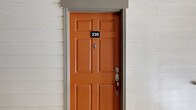 This well-appointed 1-bedroom, 1-bathroom single-floor unit offers a thoughtfully designed layout that maximizes comfort and functionality. The inviting entry, marked by a distinctive orange six-panel front door, sets a welcoming tone from the moment you arrive.

The open living area is a standout feature, showcasing rich, dark hardwood flooring that flows throughout the space. Crown molding frames the room with a classic, polished finish, while a ceiling fan provides year-round comfort. A wood-burning fireplace serves as a focal point, flanked by built-in shelving that adds both character and practical storage. Large windows dressed with blinds flood the room with natural light, creating a bright and airy ambiance.

The kitchen is conveniently positioned adjacent to the living area, offering a seamless open-concept flow ideal for everyday living and entertaining.

One of the most notable features is the private balcony, which offers sweeping views of the well-maintained community grounds, lush mature trees, and the surrounding residential buildings — providing a peaceful outdoor retreat.

The unit's single-floor layout ensures ease of movement throughout, and the overall neutral color palette creates a versatile backdrop. This unit combines classic architectural details with practical amenities for comfortable, everyday living.