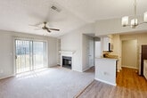 Located at 222 Kyser Blvd in Madison, Alabama, this well-appointed one-bedroom, two-bathroom residence offers a thoughtfully designed single-floor layout. The open living room is a standout, featuring vaulted ceilings, a ceiling fan, a wood-burning fireplace with a white mantel, and built-in shelving. Sliding glass doors flood the space with natural light and open to a private balcony. Flooring transitions from warm hardwood-style planks in the entryway to plush carpet in the living and bedroom areas. The galley-style kitchen is equipped with white shaker cabinets, granite countertops, stainless steel appliances including a refrigerator, electric range, and over-the-range microwave, along with a stainless steel sink. A peninsula with a granite counter connects the kitchen to the main living area. The spacious bedroom includes a ceiling fan, natural light from a window, and access to a generous walk-in closet. The two bathrooms are finished with granite-topped white vanities and hardwood-style flooring; one features a full tub-shower combination. Additional highlights include a dedicated laundry area and four closets providing excellent storage throughout.