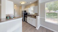 This updated single-floor residence offers two bedrooms and two full bathrooms with a cohesive, modern aesthetic throughout. The open living and dining area features wood-look hard-surface flooring, crown molding, a ceiling fan, and sliding glass doors that invite abundant natural light and outdoor views, creating a bright and welcoming atmosphere.

The kitchen is well-appointed with white shaker cabinetry, dark stone-look countertops, and black stainless steel appliances, including a refrigerator, dishwasher, and range. Wood-look flooring continues through the kitchen, which also benefits from a window view and a convenient pass-through layout connecting to the main living areas.

Both bathrooms are finished with white vanity cabinetry, dark granite-style countertops, wood-look flooring, and tiled tub-shower combinations. The design is consistent and clean across both bathrooms, offering a polished, updated feel.

The two bedrooms are carpeted and feature crown molding, ceiling fans, and windows with outdoor views of mature trees, contributing to a calm, comfortable environment. An in-unit laundry area is also present, adding everyday convenience. Throughout the residence, neutral tones and updated finishes create a cohesive and move-in-ready living space.