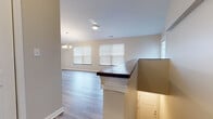 This single-floor residence at 281–293 Leydecker Road in Buffalo, NY offers a thoughtfully designed open-concept layout that connects the living, dining, and kitchen areas seamlessly. The living and dining spaces feature durable hardwood-style flooring in a cool gray tone, complemented by neutral warm-beige walls and an abundance of natural light streaming through multiple windows fitted with horizontal blinds. Elegant chandelier and pendant lighting fixtures add a refined touch throughout the common areas.

The kitchen is well-equipped with white shaker-style cabinetry, granite countertops, and a full suite of stainless steel appliances, including a gas range, over-the-range microwave, and refrigerator. A peninsula with granite countertop and seating overhang connects the kitchen to the dining area, creating a functional and social hub. A louvered closet door nearby provides convenient in-unit storage or laundry access.

The bedrooms offer plush wall-to-wall carpeting, ceiling fans, and generous windows that bring in natural light. Closet space is well incorporated. The bathroom features a full tub-shower combination, a white vanity with granite countertop, and hardwood-style flooring, maintaining a consistent, clean aesthetic throughout the unit.