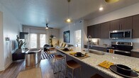 This thoughtfully designed single-floor residence offers a seamless blend of modern style and functional living. The open-concept layout connects the kitchen and living area, creating a spacious, airy atmosphere ideal for both everyday living and entertaining. The kitchen is a standout feature, equipped with dark espresso cabinetry, granite countertops, a large center island with bar seating, stainless steel appliances, and a white subway tile backsplash. Pendant lighting adds a warm, contemporary touch overhead. The living room is bright and welcoming, with wood-style flooring, a ceiling fan, and French doors that open to a private outdoor area, allowing natural light to pour in. The bedroom offers a comfortable retreat with plush carpeting, large windows dressed with blinds and curtains, and a built-in closet for storage. The bathroom continues the home's refined aesthetic with granite-topped cabinetry and direct access to a walk-in closet. The entryway is clean and practical, featuring wood-style flooring and easy access to the bathroom. Throughout the residence, a cohesive neutral palette, quality finishes, and modern fixtures create a polished, contemporary ambiance.