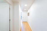 This thoughtfully designed single-floor residence offers a clean, modern aesthetic carried consistently throughout each space. The kitchen is a standout feature, showcasing warm wood-tone cabinetry that extends to the ceiling, crisp white quartz countertops, a textured tile backsplash, and a full suite of stainless steel appliances including a refrigerator, range, microwave, and dishwasher. A marble-topped island provides additional prep space and casual seating, while under-cabinet lighting adds a polished finishing touch. The living area is bright and welcoming, benefiting from a large window that frames outdoor views and fills the room with natural light. Light hardwood flooring runs throughout the main living spaces, lending warmth and continuity to the open layout. The bedroom offers plush carpeting, a generously sized closet with built-in shelving, and its own window for natural light. The bathroom is finished with large-format tile flooring, a wood-accented vanity with a white countertop, and a full shower. A dedicated hallway laundry area with a stacked washer and dryer adds everyday convenience. Recessed lighting throughout enhances the clean, contemporary feel of the entire residence.