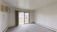 Located at 410 Glen Oaks Dr in Muskegon, Michigan, this single-floor unit offers three bedrooms and one bathroom within a compact, efficiently arranged floor plan. The living area is carpeted and bathed in natural light, thanks to a large sliding glass door that opens onto a private balcony overlooking greenery. Vertical blinds provide privacy, while baseboard heaters and a wall-mounted air conditioning unit ensure year-round comfort. The galley-style kitchen is well-appointed with white cabinetry, stainless steel hardware, wood-look vinyl flooring, a gas range with a range hood, and a double-basin sink — all laid out for efficient use of space. The three bedrooms feature plush carpeting, neutral white walls, and individual windows that bring in natural light. The spacious primary bedroom includes a closet with built-in shelving and a hanging rod for ample storage. The full bathroom is clean and functional, finished with wood-look flooring, a full tub-shower combo, and bright white surrounds. A dedicated closet provides additional storage. The unit's clean, neutral palette and practical layout make it a versatile and move-in-ready space.