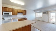 Located at 1900 Dakota Dr N in Fargo, North Dakota, this one-bedroom, one-bathroom unit offers a practical and well-organized layout across a single floor. The kitchen is a functional highlight of the space, featuring warm wood cabinetry with ample upper and lower storage, light-toned countertops, wood-look vinyl flooring, and white appliances including a range, built-in microwave, dishwasher, and double-basin sink. A peninsula counter extends from the kitchen, providing additional prep space and a casual dining option, while also defining the transition into the living area. The living space is carpeted and benefits from natural light through a window that brings in a sense of openness. The bedroom is a comfortable, well-proportioned room with plush carpet flooring, a baseboard heating unit, and a window dressed with blinds that allows for natural light and ventilation. The neutral-toned walls throughout the unit create a clean and versatile backdrop. The bathroom is fitted with a full-size soaking tub and shower combination with crisp white surround walls, complemented by a towel bar and wood-look flooring. A dedicated closet provides practical storage. The unit's straightforward design and functional layout make it a practical living space in Fargo's north side.