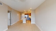 Located at 8300 NW Third St in Doral, Florida, this single-floor unit presents a clean, contemporary design throughout. The open-concept living and dining area is finished with light-toned tile flooring that runs consistently across the space, creating a seamless, airy feel. Recessed lighting illuminates the layout from above, complementing the neutral warm-beige walls and crisp white baseboards and ceilings.

The kitchen is a standout feature, outfitted with modern flat-front cabinetry in a mix of warm wood tones and cool gray finishes. Stainless steel appliances, including a large side-by-side refrigerator with an ice dispenser and a built-in oven, provide a polished, functional aesthetic. A white kitchen island anchors the space and offers additional prep and seating potential.

The bedroom is a well-proportioned, quiet room featuring a ceiling fan, light tile flooring, and a window fitted with horizontal blinds that frame exterior views. The bathroom is generously sized, showcasing a wide dual-sink vanity with white countertops, gray cabinetry, chrome fixtures, and large mirrors with integrated lighting. A glass-enclosed shower and a window adding natural light complete the bathroom's refined, spa-like character.