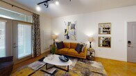 Located at 321 S Swing Rd in Greensboro, NC, this single-floor residence offers a cohesive and thoughtfully designed living experience. The living area serves as the heart of the home, featuring track lighting, warm hardwood-style flooring, and a set of French doors that invite natural light while providing outdoor access. Clean white walls provide a neutral backdrop that complements the space's contemporary aesthetic.

The kitchen is well-equipped with gray shaker-style cabinetry, granite countertops, a classic white subway tile backsplash, and a full suite of stainless steel appliances including a range, microwave, and refrigerator. A portable center island adds additional prep and storage versatility. Polished concrete flooring in the kitchen lends an industrial-modern character to the space.

The bedroom is a comfortable retreat, featuring a ceiling fan, large windows with decorative curtains that allow ample natural light, and wood-style flooring. The room offers a serene atmosphere accented by tasteful artwork.

A dedicated laundry area accommodates a stacked washer and dryer unit alongside open wire shelving for organization. This connects directly to a bathroom featuring gray cabinetry, a well-lit vanity mirror, and a bright, clean finish throughout.