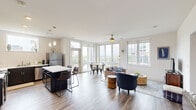 Located at 141 Wellington Pl in Cincinnati's vibrant 45219 corridor, this thoughtfully designed two-bedroom, two-bathroom residence offers a well-appointed single-floor layout with a seamless blend of modern finishes and comfortable living spaces. The open-concept living, dining, and kitchen area serves as the heart of the home, anchored by wide-plank hardwood flooring and an abundance of natural light streaming through large floor-to-ceiling windows and glass doors that frame sweeping views of the Cincinnati skyline and surrounding greenery. The kitchen features dark cabinetry, stainless steel appliances, a white countertop island with bar seating, and pendant lighting — ideal for both cooking and entertaining. The dining area sits adjacent, bathed in panoramic natural light with direct access to an outdoor terrace. The living room is bright and welcoming, with a ceiling fan and a large window overlooking the neighborhood. Both bedrooms are generously proportioned, each with ceiling fans and roller-shade windows. The primary bedroom connects to a spacious walk-in closet outfitted with wire shelving and hanging rods. The two bathrooms feature clean, neutral finishes, with white cabinetry and tile flooring. A connecting hallway ties all spaces together efficiently, completing this polished and functional urban residence.