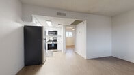 This compact yet efficiently designed 1-bedroom, 1-bathroom unit offers a clean, modern aesthetic throughout its single floor. Light wood-style vinyl flooring runs continuously across all rooms, creating a cohesive and airy feel. The open layout connects the living area to the kitchen, maximizing the sense of space.

The kitchen is a standout feature, showcasing white shaker-style cabinetry, white subway tile backsplash, and a full suite of stainless steel appliances including a refrigerator, electric range, and over-the-range microwave. A skylight adds natural brightness to the cooking space.

The living room is bright and welcoming, with large windows fitted with horizontal blinds that allow ample natural light while maintaining privacy. A ceiling fan provides comfortable airflow. The bedroom offers a similarly bright atmosphere, with a window overlooking the exterior, built-in shelving, and a ceiling fan overhead. An adjacent closet provides dedicated storage.

The bathroom features a white vanity with a quartz-style countertop, undermount sink, brushed nickel fixtures, and a large mirror — all contributing to a clean, updated look.

Throughout the unit, crisp white walls, textured ceilings, and consistent flooring create a neutral, move-in-ready environment that is both functional and inviting.