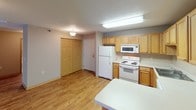 This single-floor residential unit offers a functional and comfortable layout with a cohesive neutral color palette throughout. The open-concept living and kitchen area serves as the heart of the home, featuring light hardwood-style flooring that extends from the entry through the main living spaces. The kitchen is well-equipped with warm oak cabinetry, white appliances including a range, microwave, refrigerator, and dishwasher, along with ample counter space and a sink. Overhead lighting and textured ceilings are consistent throughout the unit.

The living area is generously sized, featuring sliding glass door access that invites natural light and provides outdoor views. The bedrooms are carpeted for comfort and each includes a window with blinds, offering a quiet and restful atmosphere. Closet storage is available in the bedroom areas.

Two bathrooms serve the unit, each featuring tile flooring, a vanity with sink and mirror, and a bathtub. Warm wood cabinetry and multi-bulb vanity lighting provide a practical yet inviting finish. The overall layout is efficient and well-organized, offering comfortable living with practical storage and well-distributed natural light throughout the space.