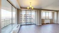 This single-floor residence offers a thoughtfully laid-out interior with an abundance of natural light throughout. The spacious living and dining area serves as the heart of the home, featuring light hardwood-style flooring, a stylish chandelier, and expansive floor-to-ceiling sliding glass doors that open onto a private balcony. Large windows frame open views of the surrounding cityscape and, in the bedrooms, striking water or horizon vistas, flooding the interior with daylight. The kitchen is efficiently designed with white cabinetry extending to the ceiling, stone-finish countertops, white appliances including a full-size refrigerator, electric range, microwave, and dishwasher, all set against light flooring for a clean, cohesive look. The bedrooms are carpeted for comfort, with generous wall space and wide windows that capture sweeping outdoor views. Two bathrooms serve the residence: one features a soaking tub with a tiled surround and a white vanity with mirrored medicine cabinet, while the second offers a stand-up shower with frosted glass doors. Neutral tones, textured ceilings, and consistent finishes throughout create a calm, functional ambiance suited to comfortable everyday living.