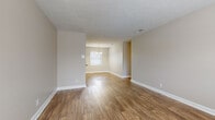 This single-floor home offers a practical and comfortable layout with a clean, neutral aesthetic throughout. The living area features warm hardwood-style flooring and a textured ceiling, with natural light filtering through slatted blinds to create a bright, welcoming atmosphere. The space flows seamlessly into a dedicated dining area, highlighted by an elegant chandelier and additional windows that further enhance the sense of openness.

The kitchen is well-appointed with white cabinetry, dark granite-style countertops, and black appliances including a range, dishwasher, and full-size refrigerator. A double sink, under-cabinet range hood, and an exterior-facing door with a window add both functionality and natural light to the space.

Multiple bedrooms are finished with plush neutral carpeting and painted in soft, warm tones. One bedroom includes a ceiling fan with integrated lighting, while others feature windows that bring in natural light. Each room offers a comfortable, versatile space suitable for various uses.

The bathroom is clean and functional, featuring a tub-shower combination with tiled surround, a vanity with a dark countertop and undermount sink, and hardwood-style flooring that ties the space together cohesively. White trim and neutral wall tones carry consistently throughout the home, contributing to a unified and inviting overall ambiance.
