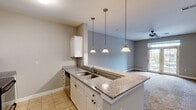 This single-floor residence offers a well-designed open-concept layout that seamlessly connects the kitchen, dining, and living areas. The kitchen is appointed with white cabinetry, granite-look countertops, stainless steel appliances including a refrigerator, electric range, and microwave, along with a peninsula featuring a double undermount sink and three pendant lights overhead. Tile flooring grounds the kitchen, while plush carpet extends throughout the living areas and bedrooms.

The spacious living room is bathed in natural light through large French doors that open to an outdoor patio, and is equipped with a ceiling fan for year-round comfort. A dedicated dining area sits adjacent to the kitchen, providing a functional transition between spaces.

The bedrooms are generously sized, each featuring ceiling fans, soft carpet, and ample closet space. One bedroom includes a walk-in closet outfitted with multiple shelving tiers and hanging rods. A second bedroom offers a standard closet and a bright window with outdoor views.

The full bathroom includes a granite-top vanity, tile flooring, and a shower-tub combination. Neutral tones in warm beige and gray are carried throughout the unit, lending a clean, cohesive aesthetic that suits a variety of interior styles.