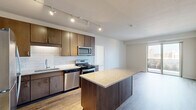 This 2-bedroom, 2-bathroom residence offers a well-designed single-floor layout filled with contemporary finishes and functional living spaces. The open-concept kitchen is a standout feature, showcasing rich dark-toned cabinetry, a classic white subway tile backsplash, granite countertops, a central island, and a full suite of stainless steel appliances including a gas range, microwave, dishwasher, and refrigerator. Track lighting overhead and wood-style flooring complete the polished look, while the kitchen flows seamlessly into the living area, which opens to a private balcony with urban city views. The bedrooms are carpeted and bright, each receiving natural light through large windows that frame city skyline views. The spacious primary bedroom is notably generous in size and is accompanied by a private en-suite bathroom featuring tile flooring, a granite-topped vanity with dark wood cabinetry, and direct access to a walk-in closet fitted with wire shelving. A second full bathroom serves the additional bedroom. The in-unit laundry area houses a stacked washer and dryer for added convenience. Throughout the residence, neutral tones and modern fixtures create a cohesive, contemporary ambiance suited for urban living.
