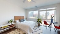 Located on E Main St in the heart of Richmond, VA, this contemporary single-floor unit offers a well-designed, open-concept layout that maximizes both functionality and comfort. The living area features warm hardwood-style flooring, clean white walls, and an airy ambiance, providing a versatile space well-suited for relaxing or entertaining. A sleek galley-style kitchen runs alongside the main living space, equipped with stainless steel appliances including a refrigerator, range, microwave, and dishwasher, complemented by white cabinetry and light quartz countertops. A breakfast bar with seating connects the kitchen to the living area, enhancing the open flow. The bedroom is a standout feature, showcasing large windows that frame impressive views of the Richmond skyline, allowing abundant natural light to fill the room. A ceiling fan adds comfort, while wood-style flooring and crisp white walls contribute to the room's clean, modern aesthetic. The bathroom is thoughtfully appointed with white cabinetry, a soaking tub and shower combo, and the added convenience of a stacked in-unit washer and dryer. Throughout the space, the design emphasizes a bright, minimalist aesthetic with modern finishes, making this unit a functional and stylish urban retreat in downtown Richmond.