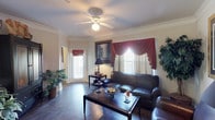 This single-floor, two-bedroom, two-bathroom residence offers a thoughtfully designed layout with consistent dark hardwood-style flooring and crown molding throughout, lending a cohesive and polished aesthetic. The living room serves as the central gathering space, featuring a ceiling fan, natural light from multiple windows dressed with decorative draping curtains, and ample room for comfortable seating arrangements. Crown molding adds an elegant architectural detail that carries through the common areas.

The kitchen is equipped with white cabinetry, dark granite-style countertops, and a peninsula with bar seating for two—ideal for casual dining. A full-size refrigerator and range are included, and the open-concept design connects the kitchen conveniently to the living area.

Both bedrooms are generously proportioned with large windows that allow natural light, and each features the same rich hardwood-style flooring. One bedroom includes a spacious walk-in closet with wire shelving, providing substantial storage capacity. The two bathrooms each include a tub-shower combination, white vanity cabinetry, and dark countertops, maintaining a consistent design language throughout the residence.
