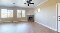Located in Gilbert, AZ, this well-appointed 2-bedroom, 2-bathroom residence offers a thoughtfully designed single-level layout. The open-concept living and kitchen area serves as the heart of the home, featuring warm wood-look flooring, crown molding, and a ceiling fan overhead. Large windows flood the living room with natural light and offer pleasant outdoor views, while a tile-surround fireplace with a white mantel adds a cozy focal point to the space. The kitchen is equipped with rich cherry wood cabinetry, dark granite countertops, and a center island with a sink and pendant lighting above. Track lighting and additional pendant fixtures complete the kitchen's functional and stylish design. Both bedrooms are carpeted and generously sized, each with ceiling fans and ample natural light. The primary bedroom includes direct access to a private bathroom featuring a glass-enclosed shower, wood-toned vanity, and hardwood-style flooring. A second full bathroom serves the additional bedroom. Two closets provide well-organized storage with built-in shelving and hanging rods. The dedicated laundry room includes a full-size washer and dryer and additional hardwood-style flooring, adding everyday convenience to this comfortable Gilbert residence.