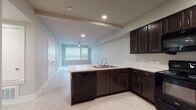 This single-floor unit offers a thoughtfully designed open-concept layout that seamlessly connects the kitchen and living area. The kitchen is a standout feature, equipped with rich dark espresso cabinetry, white countertops, and black appliances including an electric range, built-in microwave, dishwasher, and refrigerator. A peninsula counter extends into the living space, providing a natural divide while maintaining an open, connected feel. Recessed lighting and a ceiling fan enhance the functionality of the main living area, which is bathed in natural light from a large window fitted with horizontal blinds.

Light-toned tile flooring runs consistently throughout the entire unit, lending a clean and cohesive aesthetic. Multiple bedrooms offer ceiling fans, generous windows with blinds for natural light and privacy, and neutral warm-beige walls that create a calm, inviting atmosphere. The bathrooms are finished with dark vanity cabinetry, white countertops, and well-lit mirrors, maintaining the same refined color palette found throughout the home. A utility/laundry area is also visible within the floorplan. Overall, the space presents a modern, functional design with a neutral palette that provides an ideal canvas for personalization.