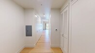 Located at 517 W Main St in downtown Madison, Wisconsin, this thoughtfully designed single-floor unit offers a clean, modern aesthetic with high-quality finishes throughout. The space is defined by a striking natural wood plank ceiling that adds warmth and character, complementing the light hardwood flooring that runs seamlessly from room to room.

The kitchen is a standout feature, showcasing a full run of flat-front, matte gray cabinetry — both upper and lower — paired with light stone countertops and under-cabinet lighting. Stainless steel Bosch appliances include an induction cooktop, built-in oven, refrigerator, and a single-basin sink, making the kitchen fully equipped and highly functional despite its efficient footprint.

The open living area benefits from a large sliding window dressed with linen curtains, inviting abundant natural light and offering views of the surrounding tree canopy. The bright, neutral white walls provide a clean backdrop that enhances the sense of openness. A hallway connects the spaces and provides additional storage via built-in closets. The overall ambiance is calm, minimalist, and modern — ideal for those who appreciate refined design in a compact, well-located urban setting.