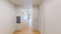 Located at 517 W Main St in downtown Madison, Wisconsin, this thoughtfully designed single-floor unit offers a clean, modern aesthetic with high-quality finishes throughout. The space is defined by a striking natural wood plank ceiling that adds warmth and character, complementing the light hardwood flooring that runs seamlessly from room to room.

The kitchen is a standout feature, showcasing a full run of flat-front, matte gray cabinetry — both upper and lower — paired with light stone countertops and under-cabinet lighting. Stainless steel Bosch appliances include an induction cooktop, built-in oven, refrigerator, and a single-basin sink, making the kitchen fully equipped and highly functional despite its efficient footprint.

The open living area benefits from a large sliding window dressed with linen curtains, inviting abundant natural light and offering views of the surrounding tree canopy. The bright, neutral white walls provide a clean backdrop that enhances the sense of openness. A hallway connects the spaces and provides additional storage via built-in closets. The overall ambiance is calm, minimalist, and modern — ideal for those who appreciate refined design in a compact, well-located urban setting.