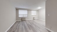 Located at 75 Windermere Ave, Suite 310 in Toronto's Swansea neighbourhood, this one-bedroom, one-bathroom unit offers a thoughtfully laid-out single-floor plan finished with contemporary light grey laminate flooring throughout. The open living and dining area is a standout feature, boasting dual windows fitted with roller blinds that fill the space with natural light, complemented by classic white radiator units beneath each window. The neutral grey and white colour palette lends a clean, modern ambiance throughout. The galley-style kitchen is efficiently designed with crisp white shaker cabinetry, dark countertops, a stainless steel sink, and full-size stainless steel appliances including a refrigerator and stove. The bedroom is a comfortable, well-proportioned space featuring its own window with a radiator below and a mirrored sliding-door closet that enhances the sense of space. A second closet provides additional storage. The bathroom is finished in bright white subway tile surrounding a full soaker tub with shower, paired with a pedestal-style sink and mirrored medicine cabinet. A dedicated entrance and additional unclassified space complete this practical, move-in-ready unit.