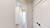 This well-appointed single-floor residence offers a thoughtfully designed layout encompassing two bedrooms, two bathrooms, a combined kitchen and living area, a dedicated closet, and a connecting hallway. The open-concept kitchen and living space serves as the heart of the home, featuring light wood-style flooring that extends throughout the main areas. The kitchen is outfitted with white shaker-style cabinetry, neutral quartz-tone countertops, a herringbone tile backsplash, stainless steel appliances including a range, microwave, and refrigerator, and a substantial island with pendant lighting overhead — providing both ample prep space and a natural gathering point.

The living area benefits from multiple windows fitted with white blinds, allowing natural light to fill the space and offering views of the surrounding neighborhood. Both bedrooms are carpeted for comfort, with the primary bedroom featuring a ceiling fan and dedicated closet space equipped with built-in shelving and hanging rods. The two bathrooms are finished in a clean, modern style, each including a tub-shower combination with large-format tile surrounds and matte black hardware accents. A bright hallway with recessed lighting connects the rooms, contributing to the cohesive, contemporary feel present throughout the residence.