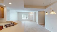 This single-floor residence offers a thoughtfully designed layout that balances comfort and functionality throughout. The open-concept living and dining area greets visitors at the front entry, featuring plush wall-to-wall carpeting, neutral-toned walls, and a large window that fills the space with natural light and views of surrounding greenery. A kitchen counter with a sink overlooks this common area, reinforcing the open flow of the floor plan.

The kitchen is well-appointed with warm wood cabinetry, a ceiling fan with light fixture, tile flooring, and a full suite of white appliances including an electric range, microwave, refrigerator, and dishwasher. A dedicated pantry provides additional storage just off the kitchen.

The bedrooms are carpeted and bright, each featuring windows that invite natural light. Ceiling fans are present in select rooms. Both bedrooms are served by generously sized walk-in closets outfitted with wire shelving systems for organized storage.

Two full bathrooms feature tile flooring and extended white vanities with ample cabinetry. One bathroom includes a tub-shower combination, while the other offers a standalone glass-enclosed shower. The attached two-car garage provides secure parking and additional utility space with an automatic opener installed overhead.