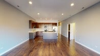 Located in Chicago's Dunning neighborhood, this single-floor residence at 2827 N Natoma Ave offers a thoughtfully designed open-concept layout with a seamless flow between living and kitchen spaces. Rich, dark hardwood floors run throughout, providing warmth and continuity across the entire home.

The kitchen is a standout feature, showcasing floor-to-ceiling rich mahogany cabinetry, light quartz countertops, and a full suite of stainless steel appliances including a gas range, built-in microwave, refrigerator, and dishwasher. A central island provides additional prep space and serves as a natural gathering point, while recessed lighting illuminates the area throughout.

The spacious living area benefits from an open connection to the kitchen and is bathed in natural light from well-positioned windows. The bedrooms are generously proportioned, each featuring hardwood floors, neutral gray walls, and windows that bring in natural light.

The bathrooms are finished with dark, large-format wall and floor tiles that create a sleek, modern aesthetic. The primary bathroom includes a dual-sink vanity with a wide mirror and dark wood cabinetry, while the secondary bathroom features a soaking tub with full tile surround. Together, these spaces deliver a clean, contemporary feel throughout the home.