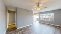 Located at 201 Los Arbolitos Blvd in Oceanside, California, this single-story home offers a clean, updated interior with a cohesive design throughout. Wood-look plank flooring runs through the entire space, providing a warm and durable foundation in every room.

The main living area is open and well-lit, featuring a ceiling fan with light fixture, soft gray walls, and a combination of sliding glass doors and windows that allow natural light to flow in and provide views of the outdoor surroundings. The layout flows naturally into the rest of the home via a central hallway.

The galley-style kitchen is efficiently designed with white cabinetry, light stone-look countertops, a stainless steel sink, and white appliances including a gas range and refrigerator. A passthrough hallway connects the kitchen to the bathroom and other areas of the home.

The bathroom is well-appointed with a wide vanity featuring white cabinetry, stone-look countertops, a large mirror, and a separate tub/shower combination. Additional bedrooms are bright and comfortably sized, each with windows fitted with blinds that allow for natural light and privacy.

The entryway is clean and practical, with ample access to closet and storage space. Throughout the home, consistent gray wall tones and white trim create a modern, move-in ready aesthetic suitable for a variety of lifestyles.