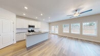 Located at 2367 Whitburn Road in Lawrenceville, GA, this two-story home offers four bedrooms and four bathrooms across a well-planned layout. The main level features an open-concept kitchen and living area bathed in natural light from large windows and French doors. The kitchen is outfitted with white shaker cabinets, granite countertops, a tile backsplash, stainless steel appliances including a refrigerator, range, and microwave, and a central island with a sink. Light wood-style LVP flooring runs throughout the main level, complemented by recessed lighting and ceiling fans. A staircase with wood treads and sleek metal balusters connects the two floors. The upper level is more expansive and hosts all four bedrooms, including a primary suite with its own bathroom and a walk-in closet featuring wire shelving systems. The additional bedrooms are carpeted and receive natural light through windows with outdoor views. The bathrooms are clean and functional, with tub-shower combos. A dedicated laundry room on the upper level includes washer/dryer hookups, a utility sink, and wire shelving for added storage. Three hallways provide smooth circulation throughout both floors.