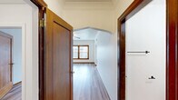 Located at 702 Martin Luther King Jr Way in Tacoma, WA, this one-bedroom, one-bathroom unit offers a thoughtfully laid-out single-floor plan. Throughout the space, light-toned hardwood-style flooring creates a clean, cohesive aesthetic complemented by crisp white walls and warm wood trim accents.

The living area is bright and airy, featuring large windows with rich wood frames that invite natural light and offer views of the surrounding neighborhood. A ceiling fan with a light fixture adds both function and character, while a classic arched doorway serves as a defining architectural detail, lending the space a timeless charm.

The kitchen is a standout feature, accessible through a distinctive pointed arch entry flanked by built-in white shelving units. White cabinetry lines the walls, paired with speckled beige countertops and a functional sink. A second kitchen area provides additional counter and storage space, accommodating a full-size refrigerator and range.

The generously sized primary bedroom includes crown molding, a ceiling fan, and direct access to a spacious walk-in closet equipped with a full-length hanging rod and ample storage capacity. The bathroom features a clean white tub-shower combination with integrated shelving. A hallway connects the rooms, contributing to the efficient and comfortable flow of the overall layout.
