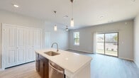 Located in Corinth, TX, this single-story 2-bedroom, 2-bathroom home offers a well-designed open-concept layout. The kitchen serves as the heart of the home, featuring rich dark-espresso cabinetry, white quartz countertops, a center island with an undermount sink, subway tile backsplash, and a full suite of stainless steel appliances including a refrigerator, range, built-in microwave, and dishwasher. Sleek pendant lighting illuminates the island, adding a modern touch. The kitchen flows seamlessly into the dining and living areas, where light wood-look flooring and neutral tones create a bright, cohesive atmosphere. Sliding glass doors lead to a private patio with outdoor views, filling the living space with natural light. The primary bedroom offers plush carpeting, a ceiling fan, and a dedicated closet, while the second bedroom features light hardwood-style flooring and a ceiling fan. Both bedrooms are served by well-appointed bathrooms with dark cabinetry and light countertops; one bathroom includes a soaking tub surrounded by classic white subway tile. A dedicated laundry area and hallway provide added convenience and functionality throughout this efficiently designed home.