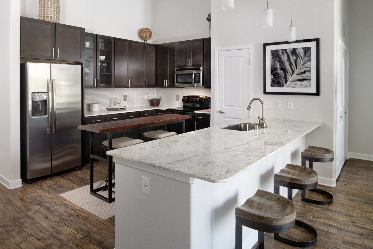 Cocina con gabinetes color espresso, encimeras de granito, placa para salpicaduras de azulejos y electrodomésticos de acero inoxidable. - Avalon Lakeside