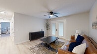 Located at 9924 Cooper Church Dr in Louisville, KY, this well-appointed 2-bedroom, 2-bathroom residence offers a thoughtfully designed single-floor layout. The open-concept living room features light wood-style flooring, a ceiling fan, and French double doors that invite natural light and provide outdoor access. The kitchen is a standout, equipped with white shaker-style cabinetry, granite-look countertops, a center island with a built-in sink, and a full suite of stainless steel appliances including a gas range, over-the-range microwave, and refrigerator. Recessed lighting and light flooring keep the space bright and modern. Both bedrooms are carpeted and include ceiling fans and windows that bring in natural light. The primary bedroom offers a comfortable, spacious feel with room for a large bed and dresser. Each bedroom is complemented by a closet featuring wire shelving systems for organized storage. The two bathrooms are clean and functional, featuring granite-topped vanities and gray cabinetry consistent with the home's modern aesthetic. A dedicated utility room rounds out the layout, adding practical convenience. Neutral tones throughout create a cohesive and inviting atmosphere across the entire residence.