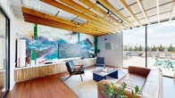 Located at 405 40th Ave N in Nashville, TN, this thoughtfully designed amenity floor delivers a compelling mix of social, recreational, and professional spaces. The standout lounge area features warm hardwood flooring, striking exposed wood beam ceilings, and floor-to-ceiling glass walls that flood the interior with natural light and open directly to an outdoor terrace with pool and skyline views. A large leather sofa, mid-century modern chairs, and vibrant large-scale artwork establish an inviting, design-forward atmosphere. Adjacent to the lounge, the dining area continues the wood beam ceiling motif and includes a substantial communal table, casual banquette seating, bistro-style tables, and a full kitchenette with cabinetry and appliances — ideal for gatherings or everyday use. A dedicated conference room offers a long wood conference table, wall-mounted display screen, built-in credenza, and curated artwork, providing a polished setting for meetings. The expansive fitness center is exceptionally well-equipped, featuring cardio machines, free weights, power racks, cable systems, a punching bag, and mirrored walls — all beneath wood-paneled ceilings with large windows offering outdoor views. Rich hardwood flooring and cohesive modern design elements unify the entire floor.