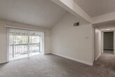 This single-floor residence offers a well-organized layout that balances open living spaces with functional private rooms. The living area immediately impresses with its vaulted, textured ceiling that lends a sense of generous vertical space. Large vertical-blind-covered sliding glass doors flood the room with natural light while providing access to the outdoors. Soft wall-to-wall carpeting extends throughout the living and bedroom areas, contributing to a warm and comfortable atmosphere.

The galley-style kitchen is efficiently designed, featuring rich dark wood cabinetry on both sides, light-toned countertops, wood-style flooring, and white appliances including a range, refrigerator, and dishwasher. A double basin sink completes the practical setup.

The bedrooms are generously proportioned, each featuring carpet flooring, textured ceilings, and windows fitted with blinds that allow for natural light and privacy. One bedroom includes a built-in louvered double closet, offering convenient storage. A hallway connects the rooms seamlessly, with wood-style flooring continuing into the entry and bathroom areas.

The bathroom is clean and straightforward, featuring a tub-shower combination with tile surround, wood-style flooring, brushed nickel fixtures, and a vanity with countertop storage. Overall, the space presents a practical and comfortable living environment.