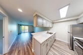 Located at 7524 35th Ave SW in Seattle's West Seattle neighborhood, this two-bedroom, one-bathroom unit offers a thoughtfully designed single-floor layout that maximizes every square foot. A clean, well-lit hallway with hardwood-style flooring welcomes you inside and leads to the main living areas.

The kitchen is a standout feature, showcasing gray shaker-style cabinetry, marble-look quartz countertops, stainless steel appliances including an electric range and refrigerator, and a skylight that floods the space with natural light. The kitchen opens directly to the living room, creating a seamless flow ideal for everyday living and entertaining. Sliding glass doors in the living area provide additional natural light and outdoor access.

Both bedrooms are carpeted and feature neutral tones, built-in closets, and windows that bring in natural light. The primary bedroom offers a comfortable footprint with its own closet storage. A total of three closets throughout the unit ensure ample storage.

The bathroom is clean and functional, featuring a full soaking tub with shower, updated brushed nickel fixtures, and a vanity with a marble-look countertop to match the kitchen's aesthetic.

Throughout the unit, warm wood-tone flooring in the main living areas and neutral paint tones create a cohesive, inviting ambiance.