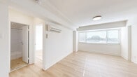 This well-appointed single-floor unit presents a clean, minimalist design centered around an open layout filled with natural light. Light hardwood flooring runs consistently throughout the living and sleeping areas, lending warmth and continuity to the space. Crisp white walls and white trim enhance the airy, bright ambiance found in every room.

The spacious main living area features a wall-mounted ductless mini-split system for climate control and wide windows fitted with horizontal blinds, allowing for ample natural light while maintaining privacy. The open sightlines connect the living area seamlessly to the galley-style kitchen, which is outfitted with white shaker cabinetry, sleek bar-pull hardware, white quartz countertops, a stainless steel sink, and a full suite of stainless steel appliances including a gas range, refrigerator, built-in microwave, and dishwasher. The kitchen also provides access to an additional room, ideal for pantry or storage use.

The bedroom offers a generous footprint with wide windows overlooking the surrounding neighborhood, a wall-mounted mini-split unit, and a closet for ample storage. The bathroom is finished with warm travertine-style tile flooring, large-format white subway tile surrounding the full soaking tub, a white vanity, and recessed lighting, completing this thoughtfully designed space.